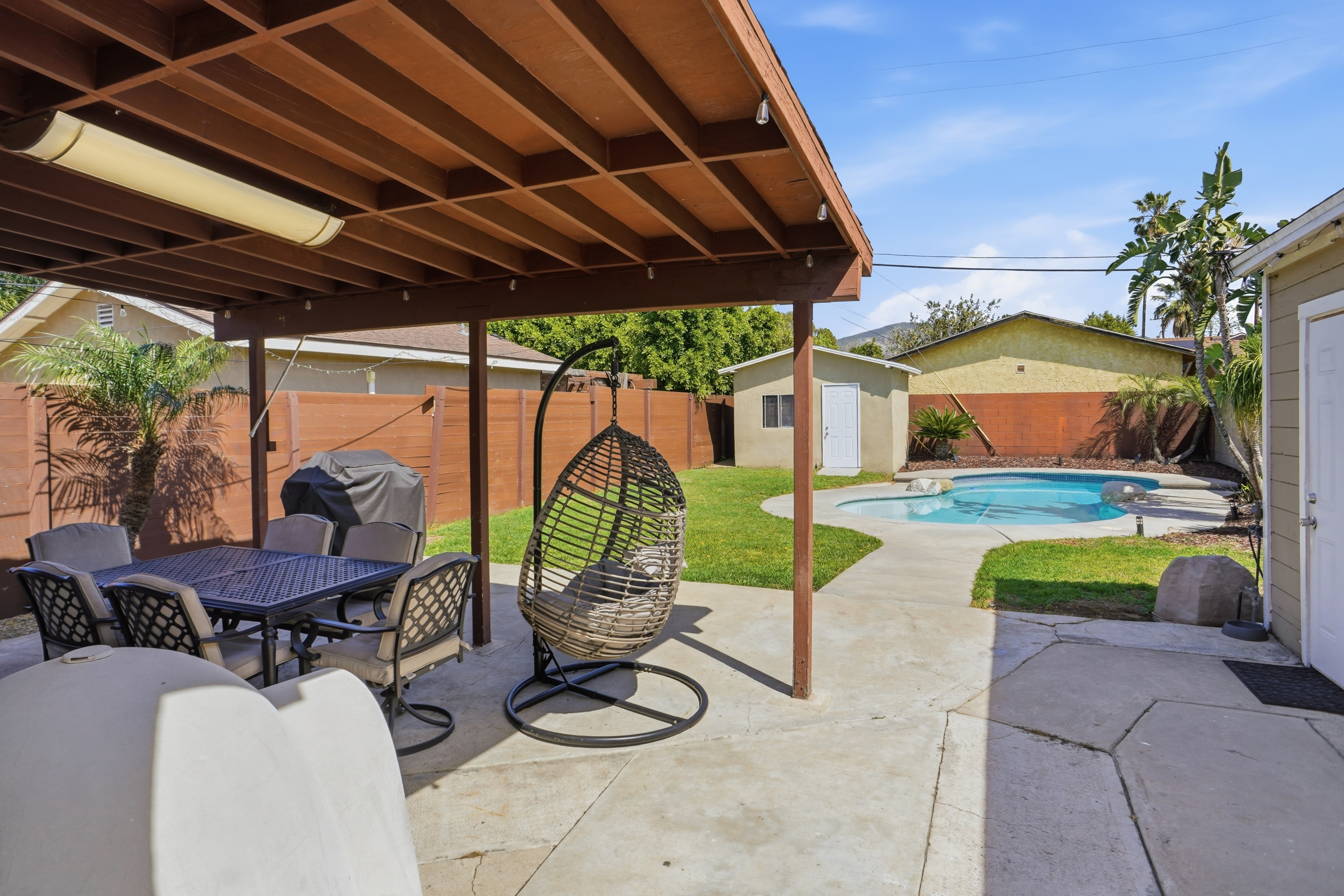 Full backyard with covered patio, pool, and shed